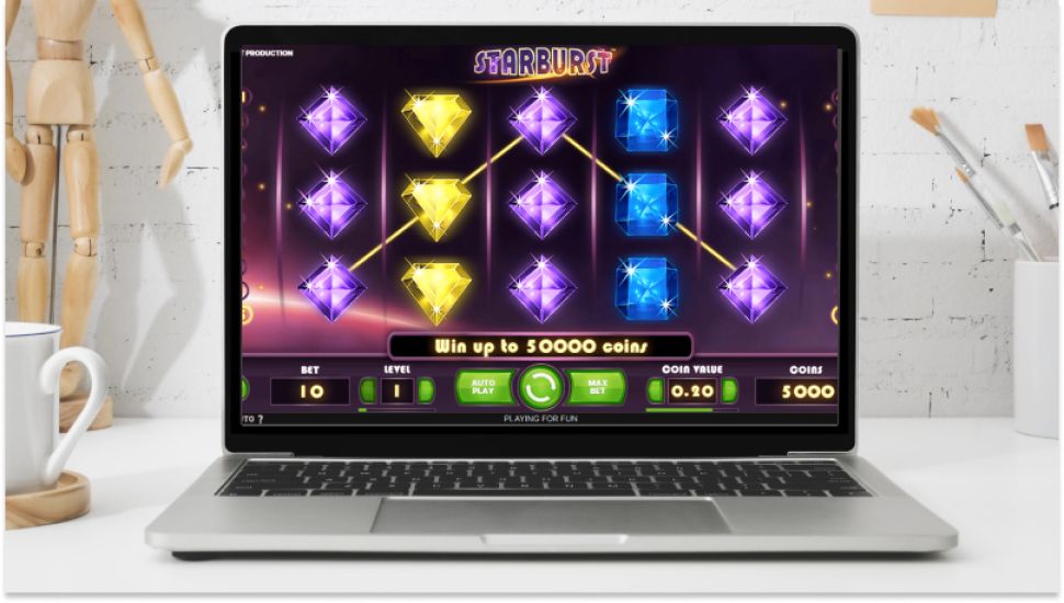 Interfejs slota Starburst pokazany na laptopie, ze świecącymi symbolami klejnot&oacute;w.